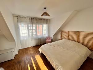a bedroom with a bed and a large window at Les appartements d'Ostende in Calais