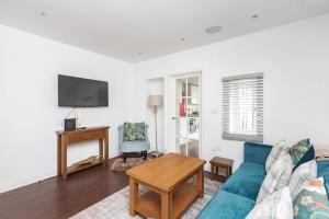 a living room with a blue couch and a tv at Sunny Terrace By Kasar Stays in Maidstone