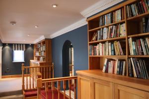 a library with wooden shelves filled with books at Leafield House Nables Farm in Chippenham