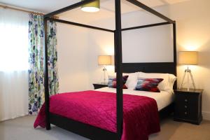 a bedroom with a four poster bed with a red blanket at Leafield House Nables Farm in Chippenham