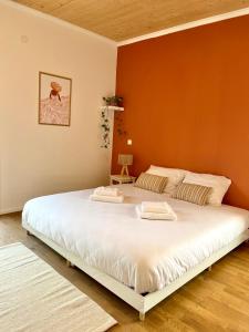 een groot wit bed in een kamer met een oranje muur bij Modern & Stylisch Penthouse - 112m2 - München&Airport in Freising