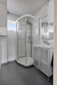 een witte badkamer met een douche en een wastafel bij Cozy 2-Bedroom Apartment - Free Parking in Haugesund