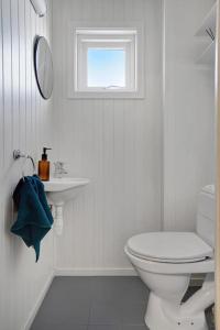 een witte badkamer met een toilet en een raam bij Cozy 2-Bedroom Apartment - Free Parking in Haugesund