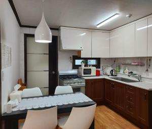 a kitchen with white cabinets and a table and chairs at Atti in Pyeongtaek
