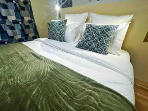 un grande letto con lenzuola e cuscini bianchi di Le cocon d'Huguette, St Denis, Paris a Saint-Denis