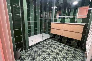 a green tiled bathroom with a sink and a shower at Le cocon d'Huguette, St Denis, Paris in Saint-Denis