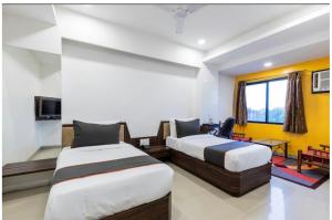 a hotel room with two beds and a tv at Kanchan Tilak in Indore