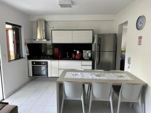 eine Küche mit einem Tisch mit Stühlen und einem Kühlschrank in der Unterkunft Genipabu Club House Guarajuba Camaçari-Ba in Camaçari