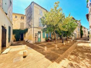 una calle vacía con un edificio y árboles delante en Terracotta Tranquility, en Arles