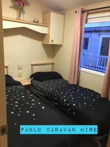 2 camas en una habitación con ventana en 2 bedroom 6 berth Caravan Towyn Rhyl en Kinmel Bay