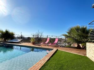 ein Schwimmbecken mit zwei rosa Stühlen und Rasen in der Unterkunft Villa contemporaine avec piscine in Magalas