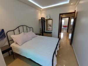 a bedroom with a white bed and a hallway at Cozy sunny apartment in Sale