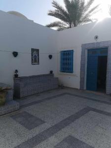 a white building with a blue door and a palm tree at Dar arbi in Houmt Souk