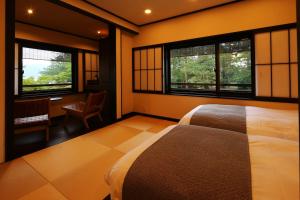 a bedroom with a bed and two windows and a desk at Taikyourou in Miyazu