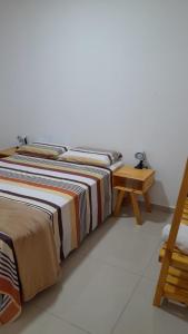 - un lit avec une couverture rayée à côté d'une table en bois dans l'établissement Condominio encantador em Parnamirim com Piscina, à Parnamirim