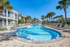 una piscina con sillas y palmeras en Destiny Beach Villas #11A- Beach Oasis, en Destin