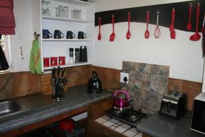 eine Küche mit roten Utensilien, die an der Wand hängen in der Unterkunft Kiburi Cottage @ Kruger in Marloth Park