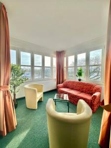 un soggiorno con divano rosso e sedie di Gästezimmer Weserblick a Berne