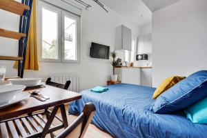 a bedroom with a bed and a table and a dining room at Studio avec mezzanine - Wifi - Proche Paris (R8) in Montreuil