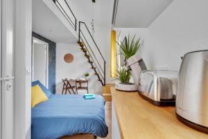 een slaapkamer met een blauw bed in een kamer bij Studio avec mezzanine - Wifi - Proche Paris (R8) in Montreuil