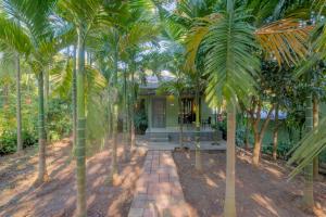 uma casa com palmeiras em frente em Silvanus Forest Retreat, Alibaug em Alibag