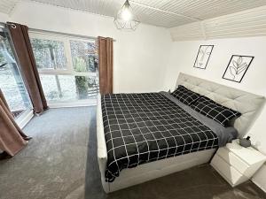a bedroom with a black and white bed and a window at Wood House Valiug in Văliug