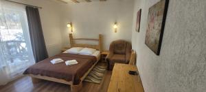 um pequeno quarto com 2 camas e uma cadeira em Готель RIVER HILL em Mykulychyn
