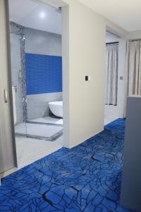 uma casa de banho com um chuveiro e um piso azul e branco em Aquarius Kigo Resort em Kigo