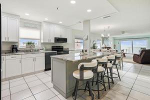 a kitchen with white cabinets and a bar with stools at Sea Breeze 401 in St Pete Beach