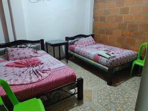 Cette chambre dispose de 2 lits, de chaises et d'un mur en briques. dans l'établissement Hospedaje la Viña, à El Cerrito