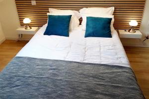 ein großes weißes Bett mit blauen Kissen im Schlafzimmer in der Unterkunft The Silent T1 city center JO 2024 PARIS in Chevreuse