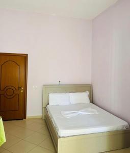 een slaapkamer met een bed en een houten deur bij Hotel Tani 