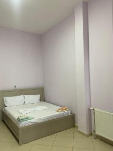Bett in einem Zimmer mit einer weißen Wand in der Unterkunft Hotel Tani 