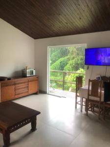 a living room with a table and a large window at Casa Cachoeira Paraty in Paraty