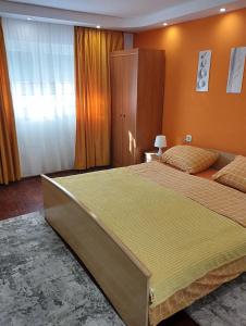 ein Schlafzimmer mit einem großen Bett und orangefarbenen Wänden in der Unterkunft Sunshine apartment near the zoo, free parking in Sarajevo