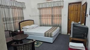 Schlafzimmer mit einem Bett, einem TV und einem Tisch in der Unterkunft city Homes in Dhaka