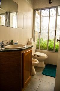 baño con lavabo y aseo y ventana en Bellamar Apart Hotel, en Bella Vista