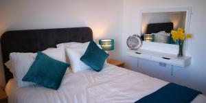 Classy yet cosy and close to Chester City Centre في تشيستر: غرفة نوم مع سرير ووسائد زرقاء ومرآة