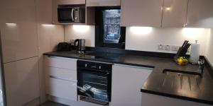 a kitchen with white cabinets and a black oven at Classy yet cosy and close to Chester City Centre in Chester