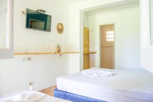 a white bedroom with a bed and a mirror at Quinta Los Lapachos de Ypané in Ypane