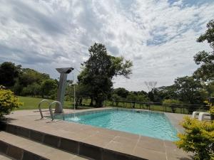 een zwembad in een tuin met een bewolkte hemel bij Quinta Los Lapachos de Ypané in Ypane