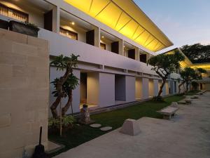 a building with a courtyard with palm trees and benches at Kuta Living in Kuta