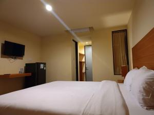 a bedroom with a large white bed and a television at Kuta Living in Kuta