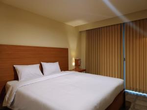 a large white bed in a hotel room at Kuta Living in Kuta