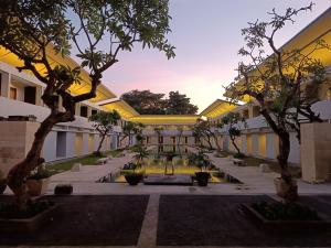 a courtyard with trees in front of a building at Kuta Living in Kuta