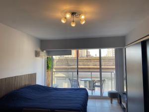 Un dormitorio con una cama azul y un balcón con una mesa. en Viamonte Suites II en Buenos Aires