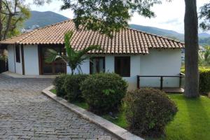 a white house with a palm tree in front of it at Casa do Deck Inesquecível - Escarpas do Lago in Capitólio