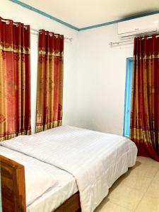 Ce lit se trouve dans un dortoir doté de rideaux rouges. dans l'établissement Batubutir homestay, à Midang