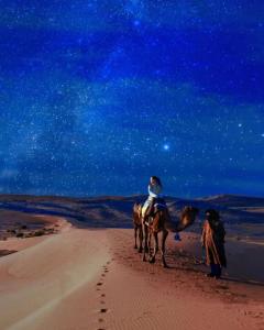 two people riding on horses in the desert at Merzouga Stars Luxury Camp in Merzouga