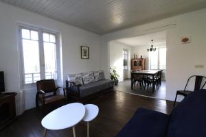 een woonkamer met een bank en een tafel bij Maison dans le bourg, 6-8 couchages avec piscine in Groléjac